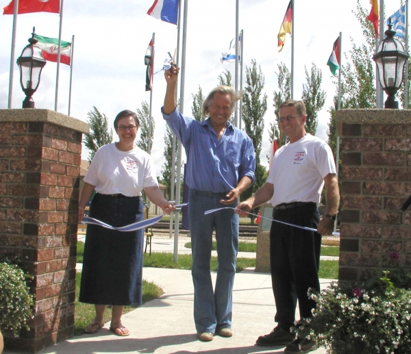 Eighteen years ago, on June 22, 2002, Peter Nygard (middle) cuts the ribbon at Nygard Park in Deloraine, flanked by Deloraine Chamber of Commerce President Dorothy Brown and Deloraine Economic Development Office Grant Cassils. The park was officially opened at the ceremony, with the day also including a parade and fashion show. Nygard had lived in Deloraine as a child before becoming a fashion icon. The community is renaming the area Prairie Sentinel Park in response to the controversies involving Nygard.