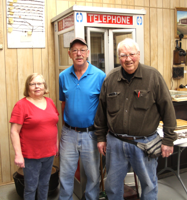 Beckoning Hills Board Members (L-R): Sandra Pearce, Eric Reichert and Ken Dixon in front of the old phone booth in the museum. They along with board members Craig Reichert, Karla Wilbee, David M. Neufeld, Betty Sawatzky and many volunteers have been working to refurbish the museum for the coming season.