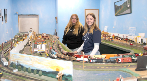 Summer students Mackenzie Reichert (left) and Erika Neufeld show off the newest addition to the Goodon International Wildlife Museum. The train display was donated by the Earl Patterson family, and was once housed elsewhere. It shows many different historical buildings in the area.