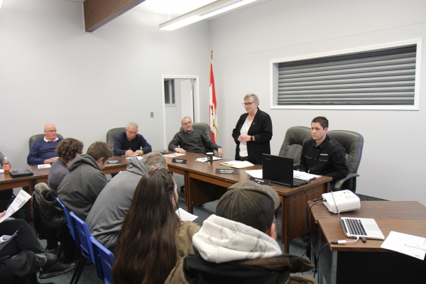 Boissevain-Morton Head of Council Judy Swanson (standing) addresses the crowd, with councillors (L-R) Rob Adams, George Heide and David Stead and CAO Leo Poulin listening. On February 25, council held a public meeting to discuss upcoming changes to the mill rate. Currently, the urban and rural wards have separate mill rates. By Provincial law, they must become one by 2023, which could have many consequences.  photo by paul rayner