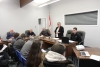 Boissevain-Morton Head of Council Judy Swanson (standing) addresses the crowd, with councillors (L-R) Rob Adams, George Heide and David Stead and CAO Leo Poulin listening. On February 25, council held a public meeting to discuss upcoming changes to the mill rate. Currently, the urban and rural wards have separate mill rates. By Provincial law, they must become one by 2023, which could have many consequences.  photo by paul rayner