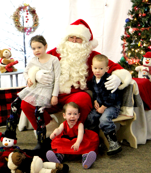 During Santa Day in Boissevain on November 26, Remington (left), Waverleigh, and Oaklin, children of Nevin and Laura Mains, take their turn on the knee of Jolly Old St. Nick. They will grow up to love Santa, of course, and this photo will be a cherished memory. 