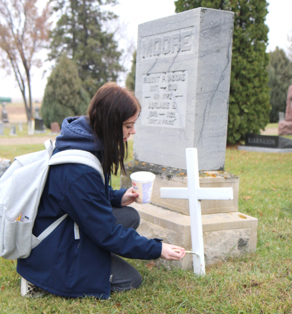 Kenzie Canada, of Boissevain School, puts a fresh coat of white paint on a veteran’s cross at a grave at Boissevain Cemetery. Some advisory groups from the school went out to honour and remember veterans by cleaning up their crosses on October 28. 